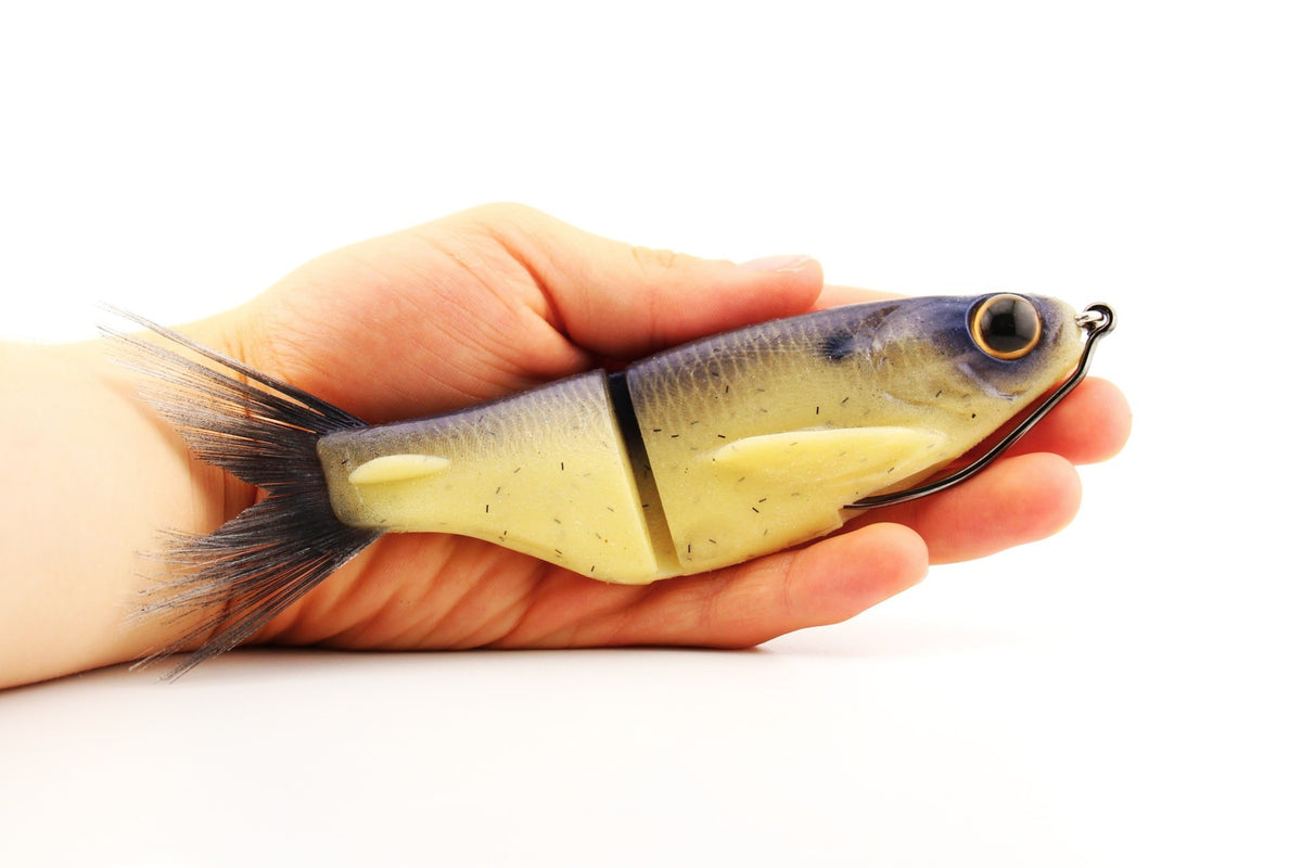 Soft Dad 6.75-inch silicone glide bait in Dry Bones color shown in hand for size reference with weedless rigging.